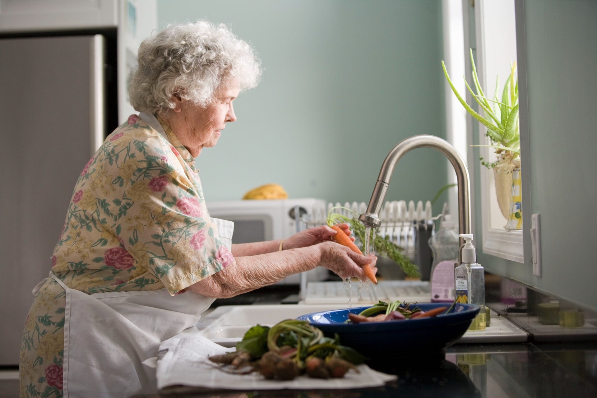 Ältere Frau wäscht Gemüse