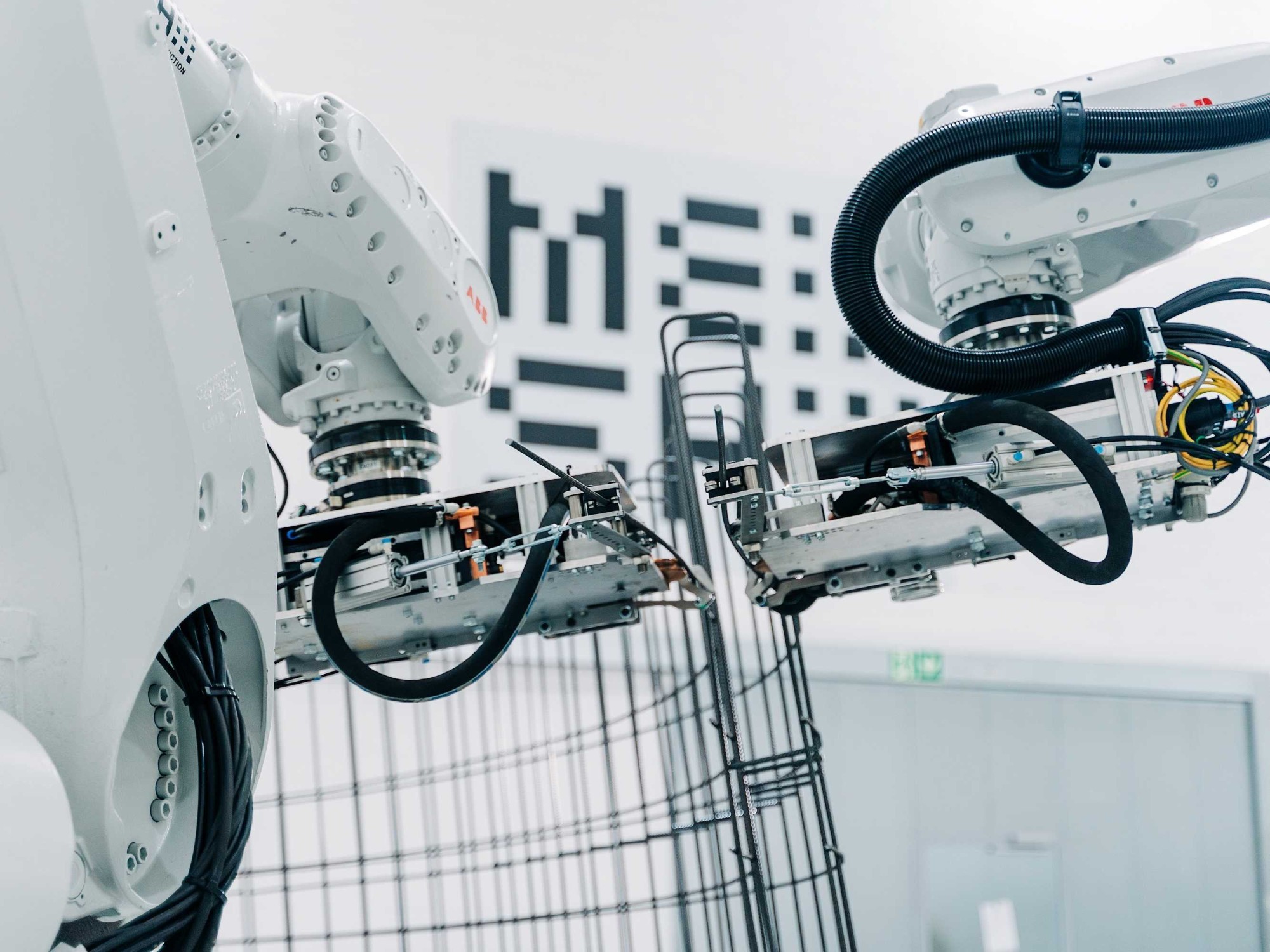Zwei Roboterarme verformen Bewehrungseisen