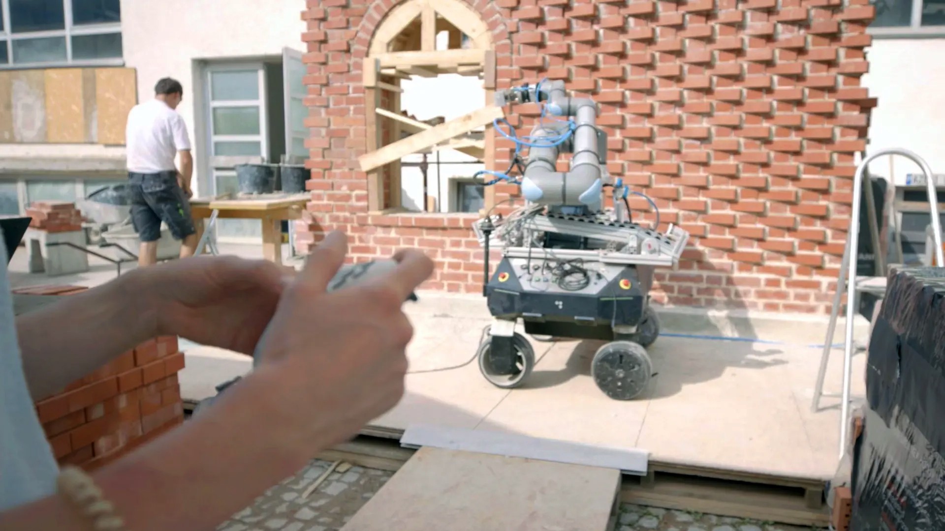 Mauerer errichten mit Unterstützung eines Roboters eine Mauer.