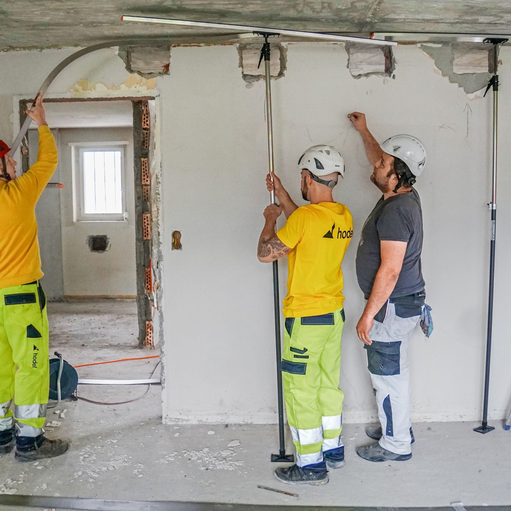 Die Metall-Bänder werden anschliessend mit mehreren Teleskopstützen an der Decke fixiert. Zwei Mitarbeiter der Firma Hodel werden eingewiesen. 