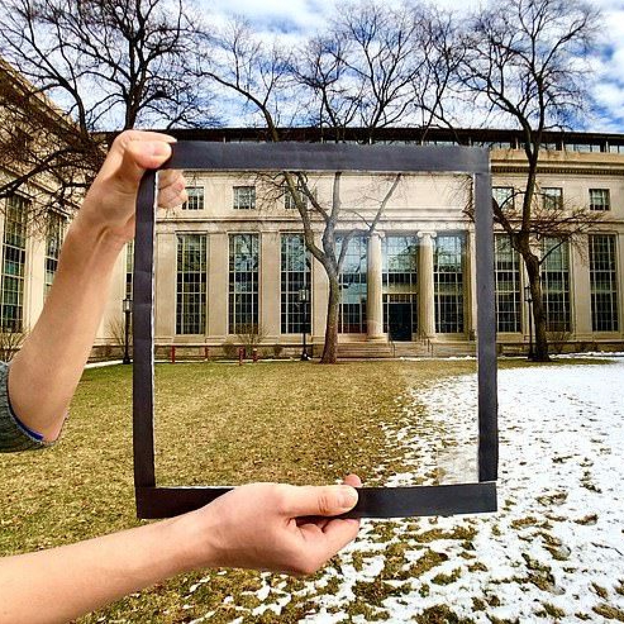 Mann hält Fensterglasscheibe mit Wärmeschutzfolie darauf, im Hintergrund ein Hof