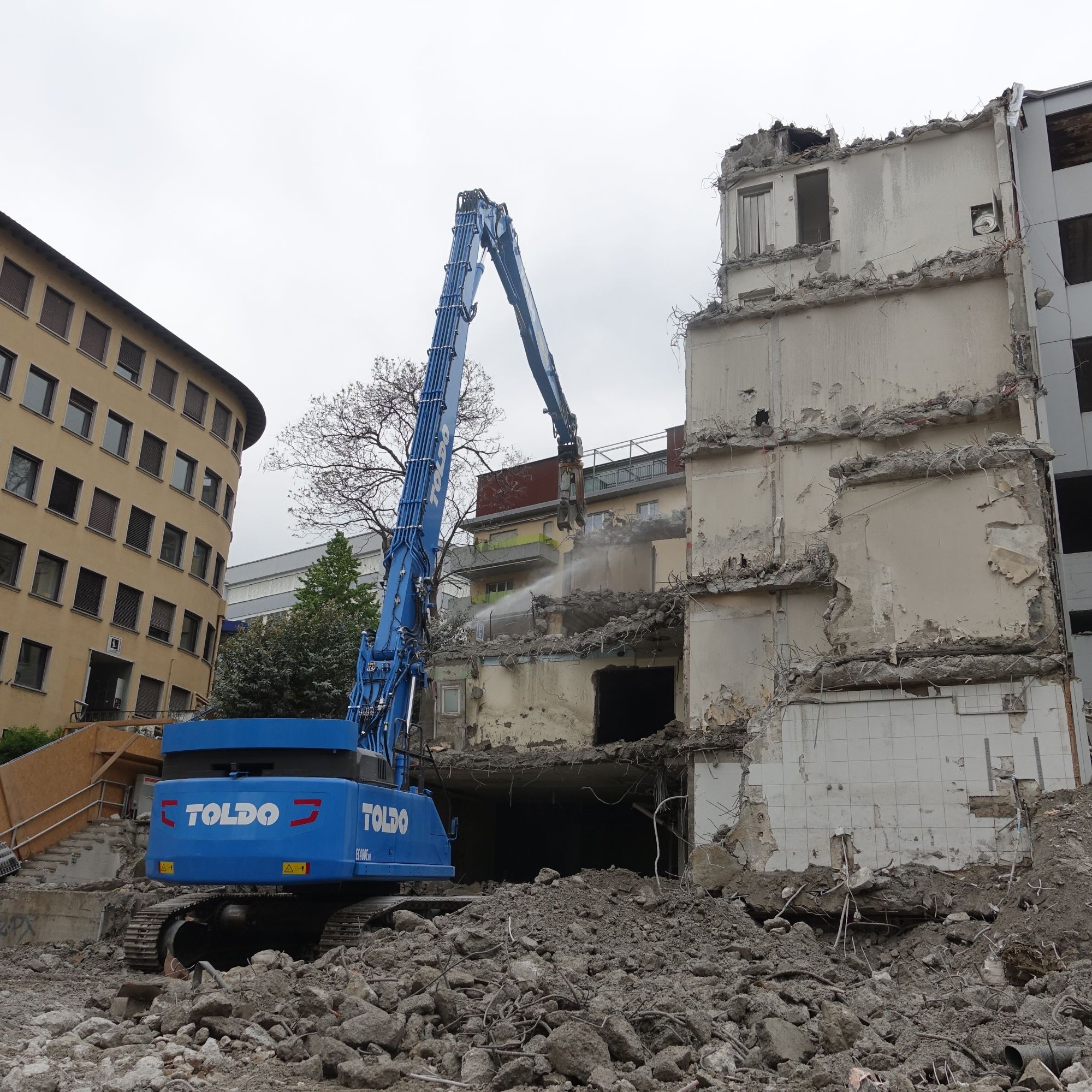 Die Baustelle liegt in dicht bebautem Gebiet. Mit dem Wasserstrahl gehen die Bauarbeiter gegen den Staub an, der beim Abbruch des Stahlbetonskeletts entsteht.