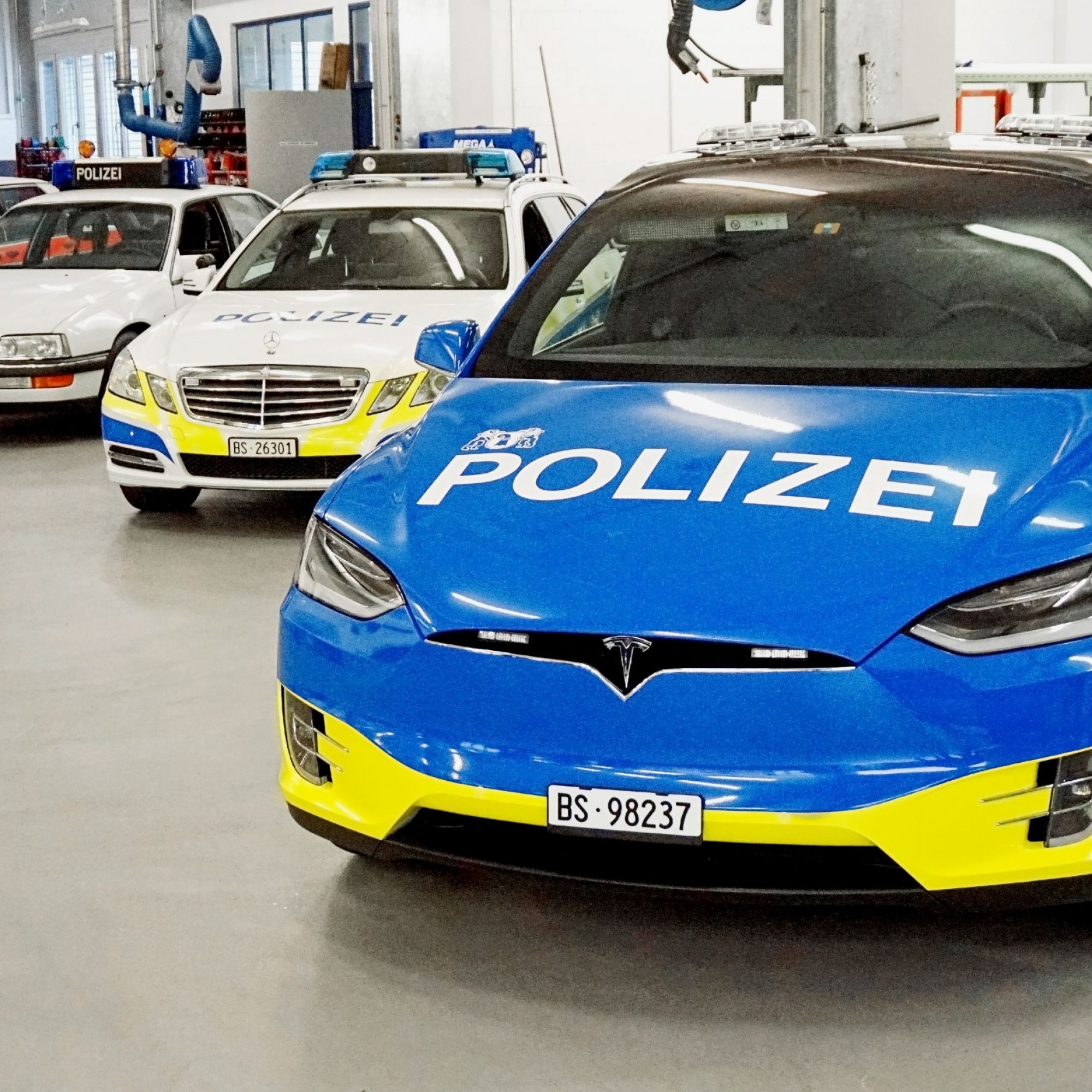 Die Alarmpikett-Fahrzeuge der Basler Polizei. Vorne der besagte Tesla, dahinter seine Vorgänger: BMW (1985), Opel (1997) und Mercedes (2013).