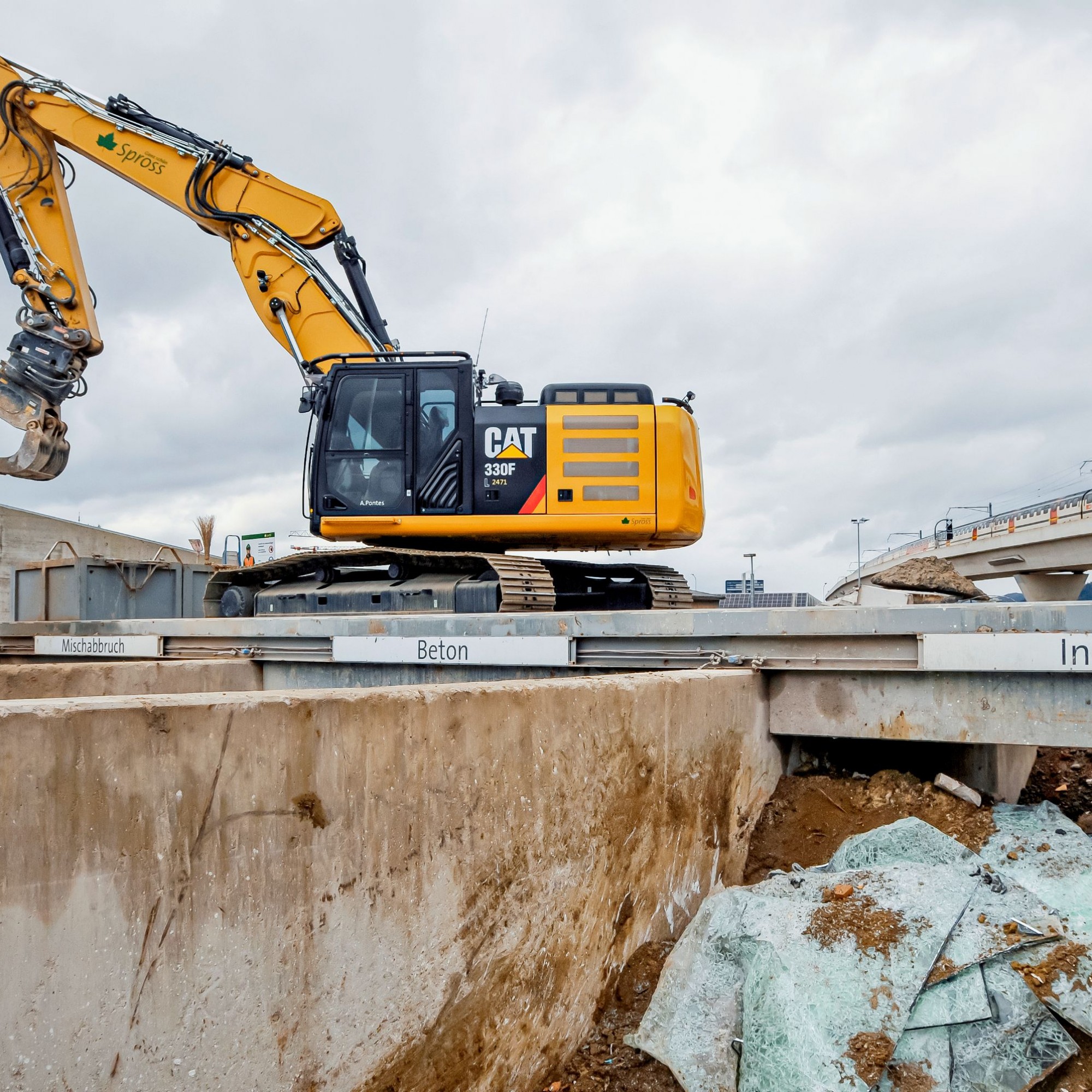 Ein Bagger entfernt Metallteile aus dem Mischabbruch. Im SBB-Zug sitzend erhält man von der Letzigrabenbrücke aus einen Blick auf das Areal des Recyclinghubs.