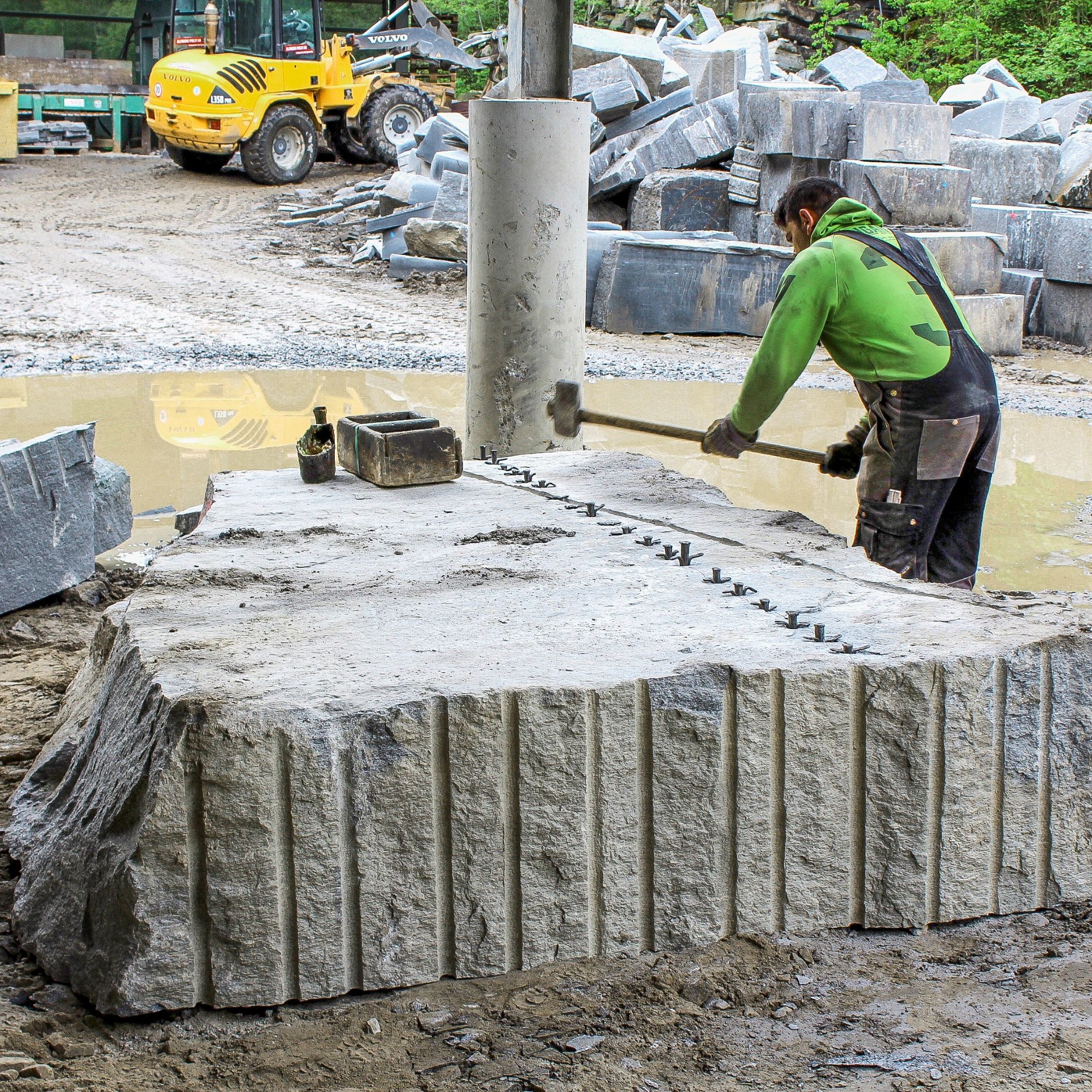 Naturstein mit dem Lager lässt sich mit geringerem Kraftaufwand spalten. Nach wenigen Schlägen des Vorschlaghammers auf die gesetzten Nägel zerbricht der Gneisblock zu kleineren Quadern.