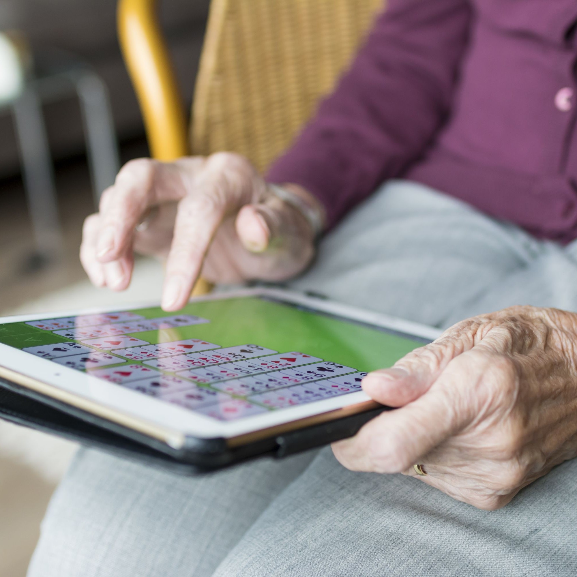 Ältere Frau spielt Solitaire auf einem Tablet