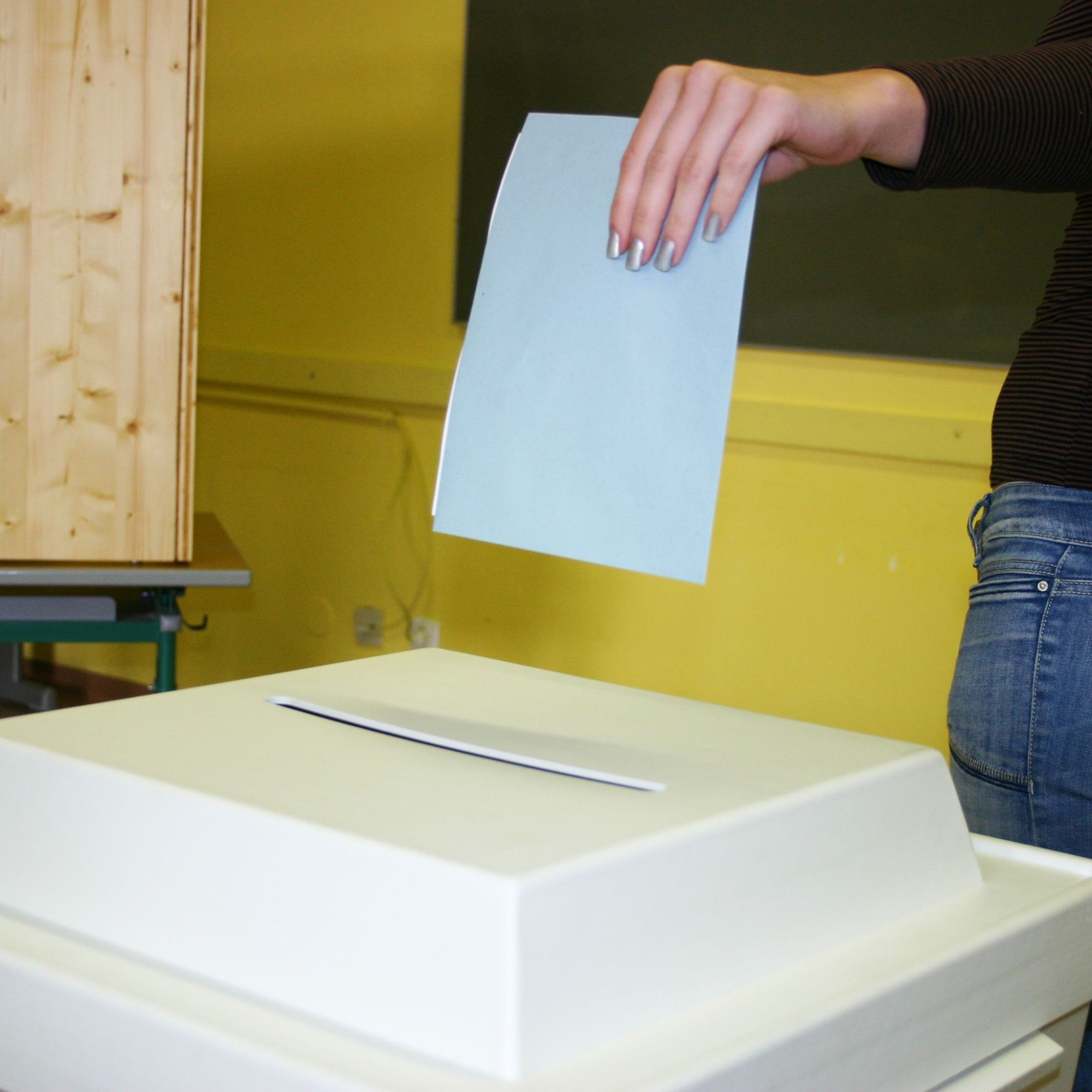 Abstimmung: Stimmzettel werden in die Urne geworfen