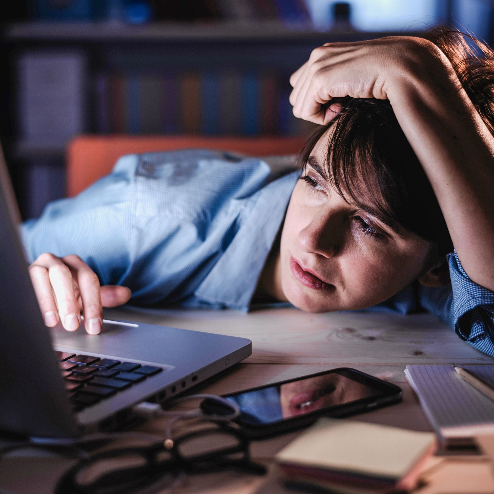 Frau sitzt genervt und müde vor dem Laptop.