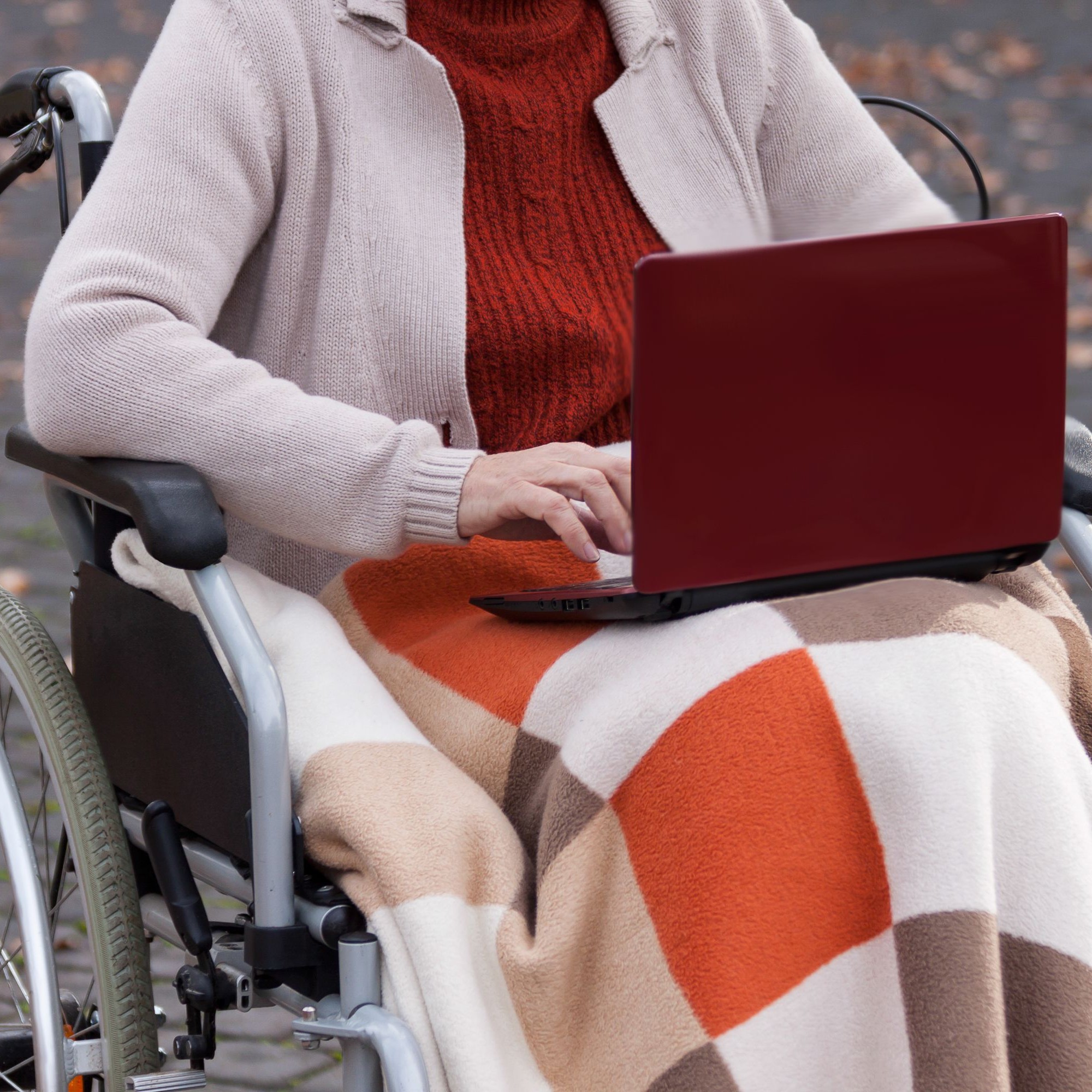 Frau mit Laptop im Rollstuhl