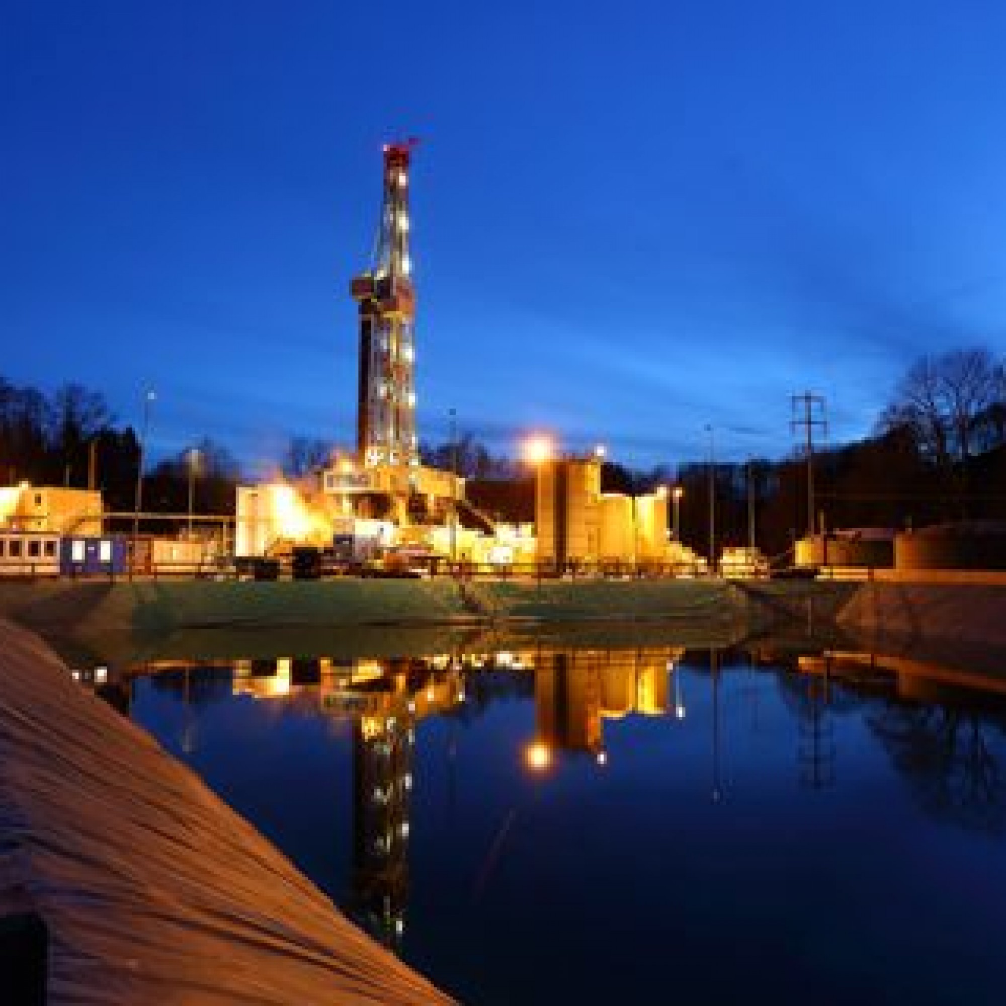 Bohranlage mit Speicherbecken bei Nacht