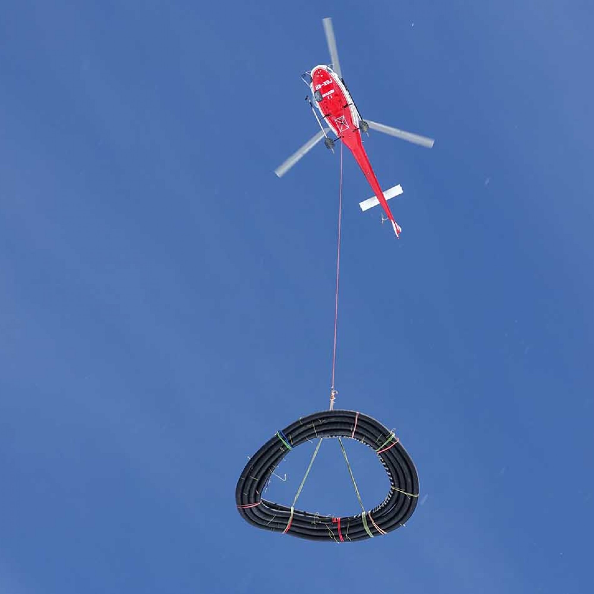 Helikopter der Air Glacier tranportiert Schlauch-Konstruktion