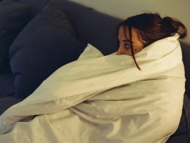 Frau mit Decke auf dem Sofa.