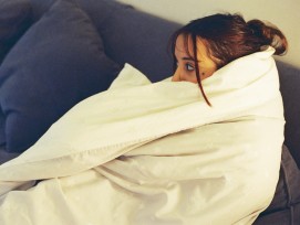 Frau mit Decke auf dem Sofa.