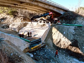 Zentimetergenauer Einbau der über sieben Tonnen schweren Stahlkonstruktion in die Aussparung der aus Beton gefertigten Wildbachsperre unter der Kantonsstrassenbrücke über den Illgraben.