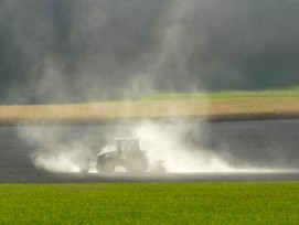 Bauer wirbelt Staub auf dem Feld auf.