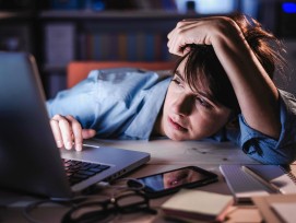 Frau sitzt genervt und müde vor dem Laptop.