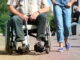 Behinderter Mann in Rollstuhl neben gesunder Frau