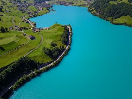 Atemberaubend blauer See mit grünen Matten und kleinem Dorf