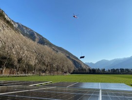 Helikopter fliegt Solarmodul vom Talboden in die Höhe.