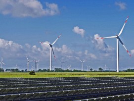 Solaranlage mit Windturbinen im Hintergrund.